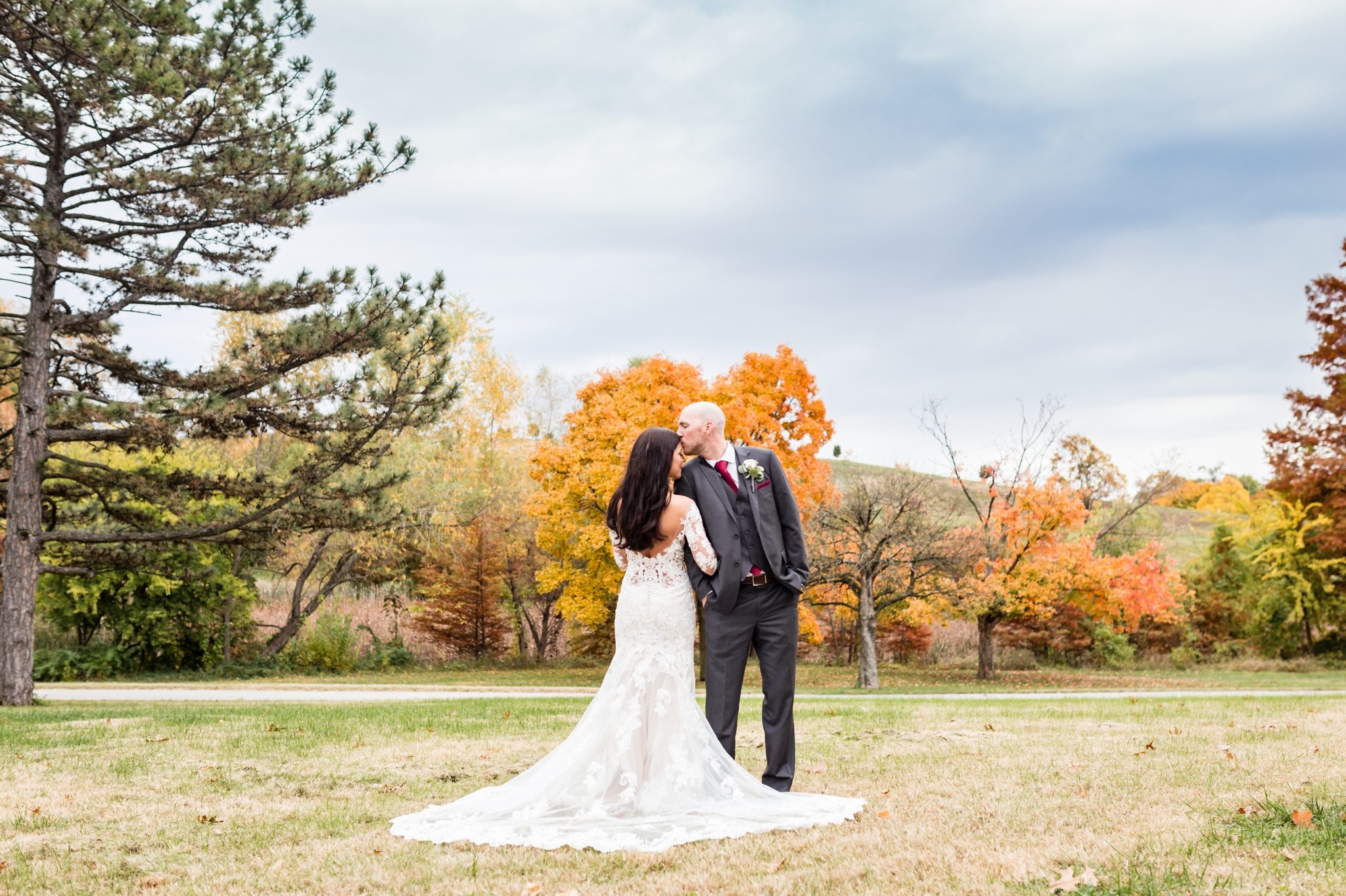 bride and groom kiss, rainy skies, fall trees, forest park