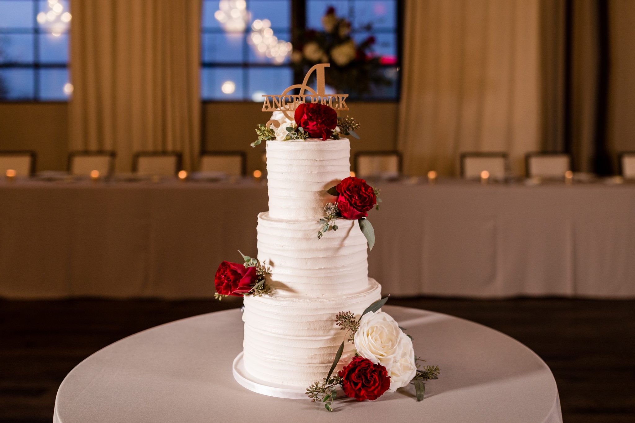 three-tier cake with roses and personalized cake topper